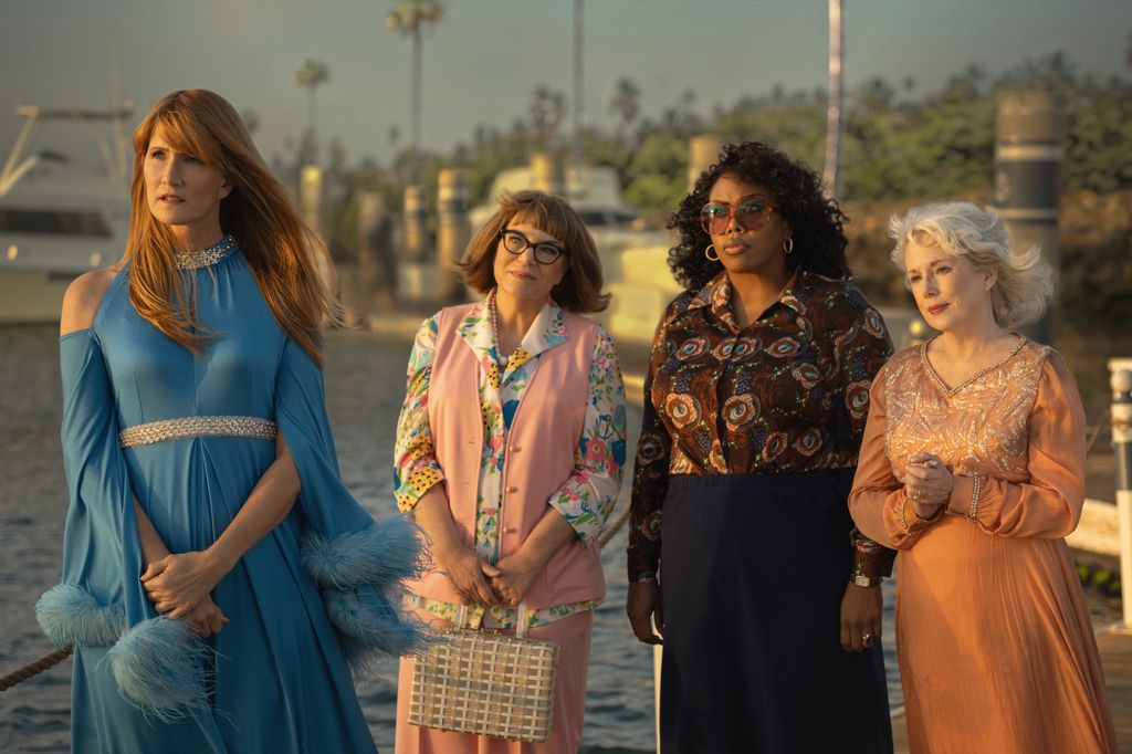 Four women in 70s outfits stand on boat