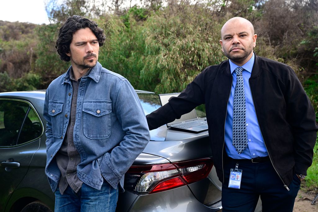 two men standing by car