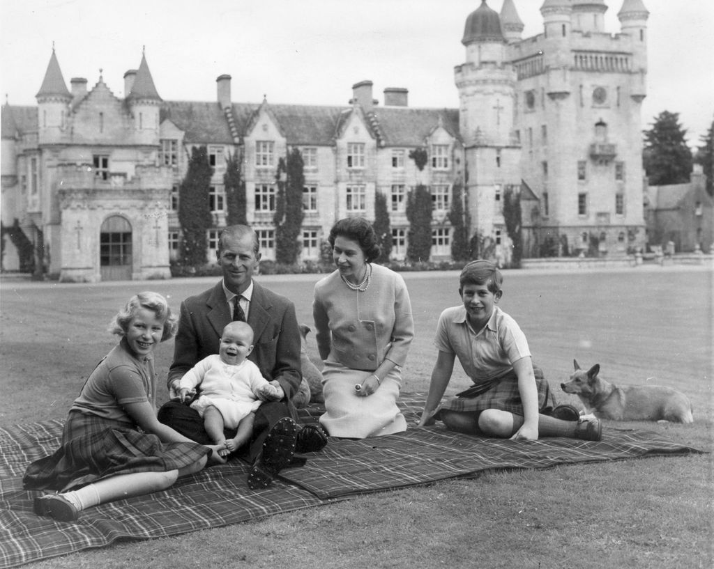 Queen Elizabeth II and Prince Philip, Duke of Edinburgh with their children, Prince Andrew, Princess Anne and Charles, Prince of Wales sitting on a picnic rug outside Balmoral Castle in Scotland, 8th September 1960