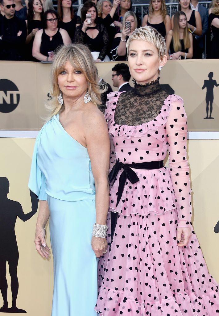 Goldie Hawn in blue on red carpet with Kate Hudson in pink and black