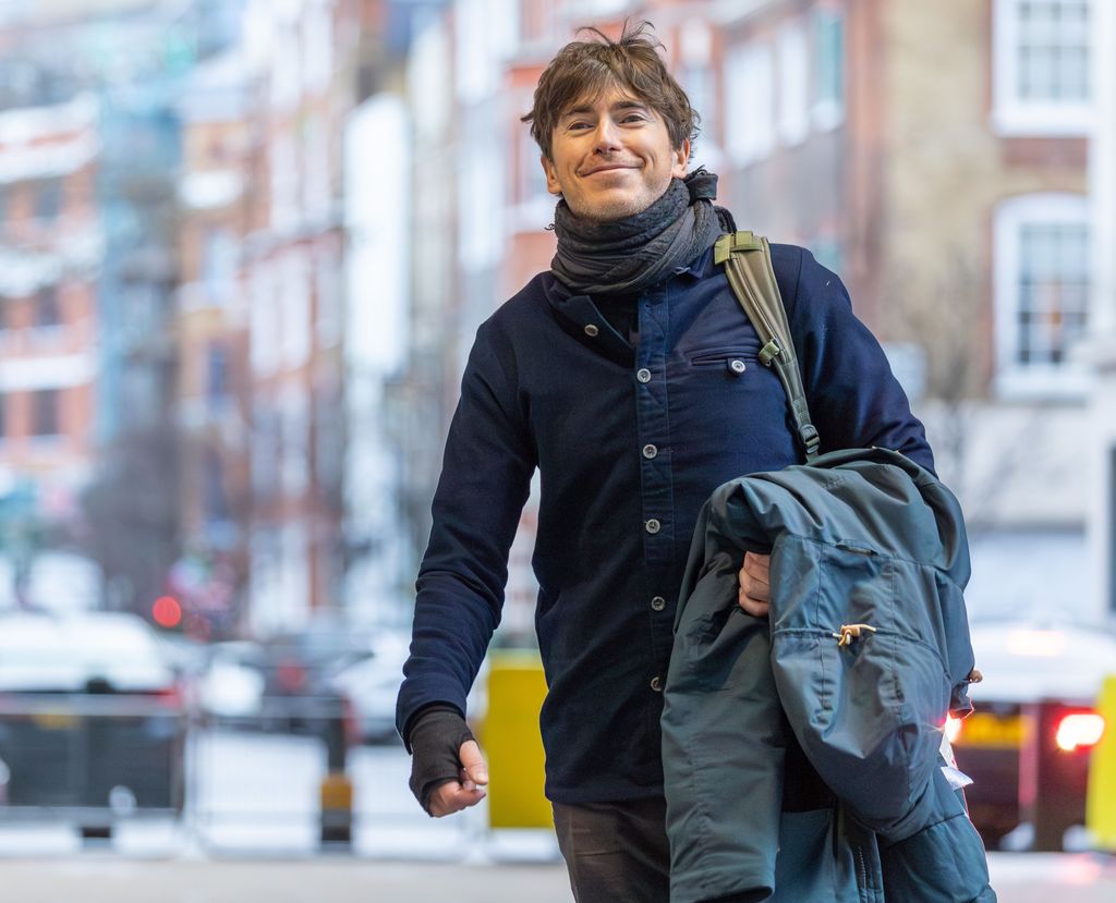 Simon Reeve holding a jacket on the street in London