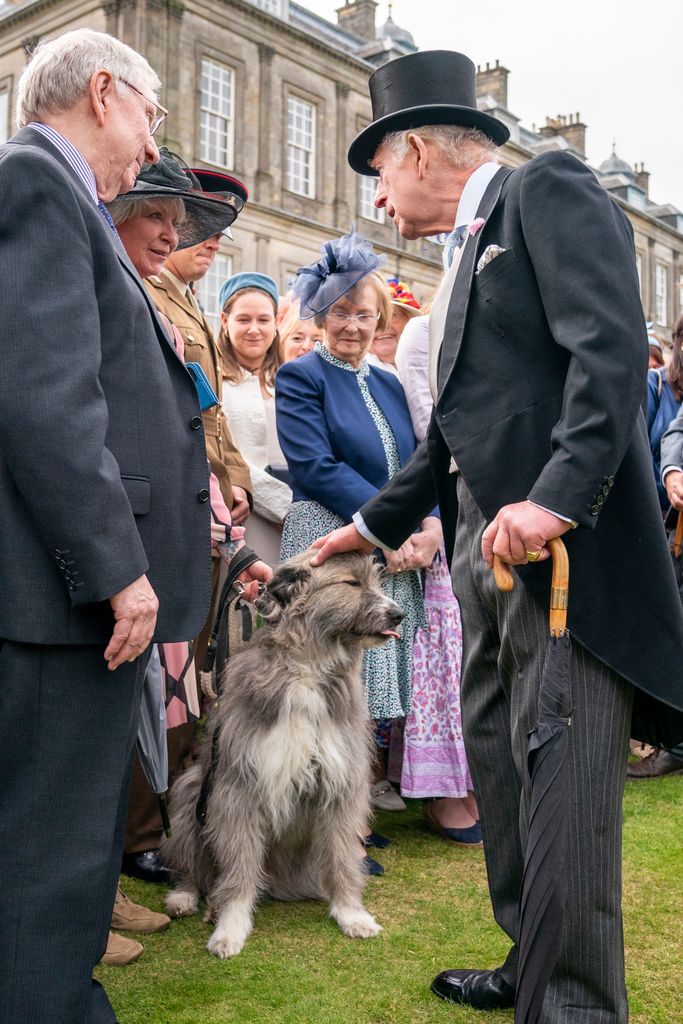 King Charles stroking dog during garden party at  Palace of Holyroodhouse