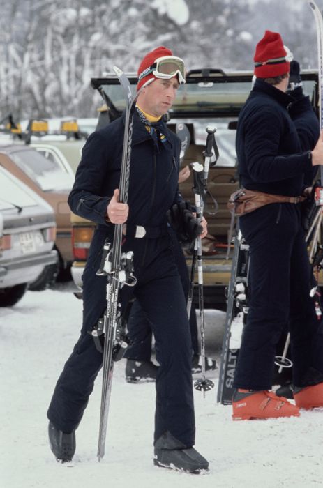 Young Prince Charles in a snowy location wearing ski gear and carrying skis