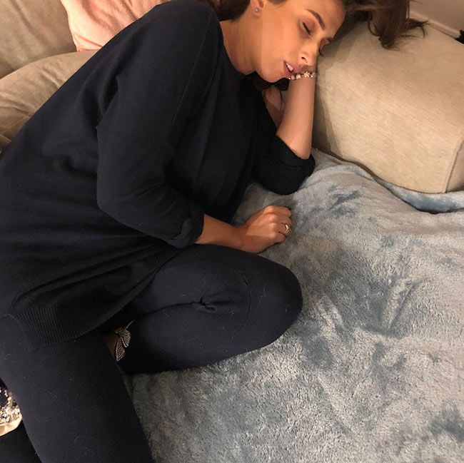 a closely cropped photo of stacey curled up and fast asleep in black loungewear on a light coloured sofa topped with a baby blue fluffy blanket