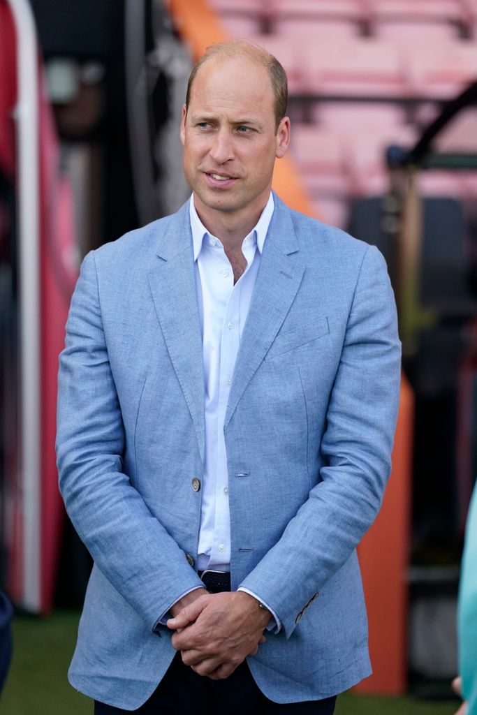 Prince William in a light blue jacket and shirt inside a football stadium