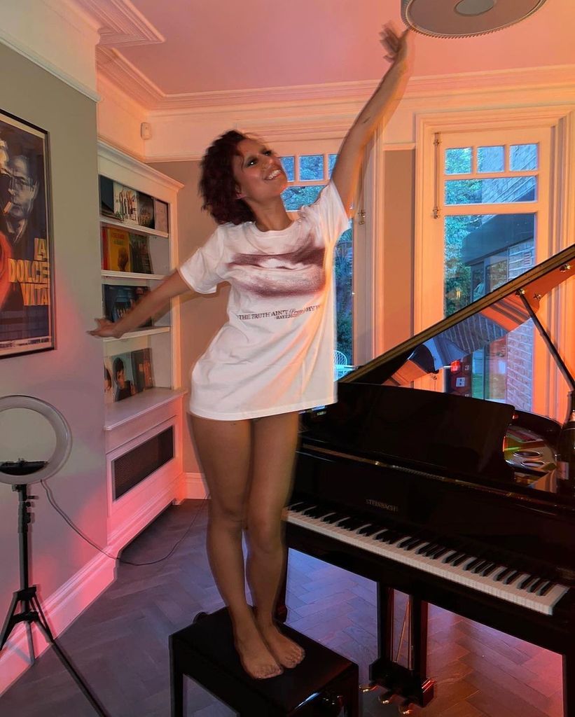 Raye standing on a stool next to a piano