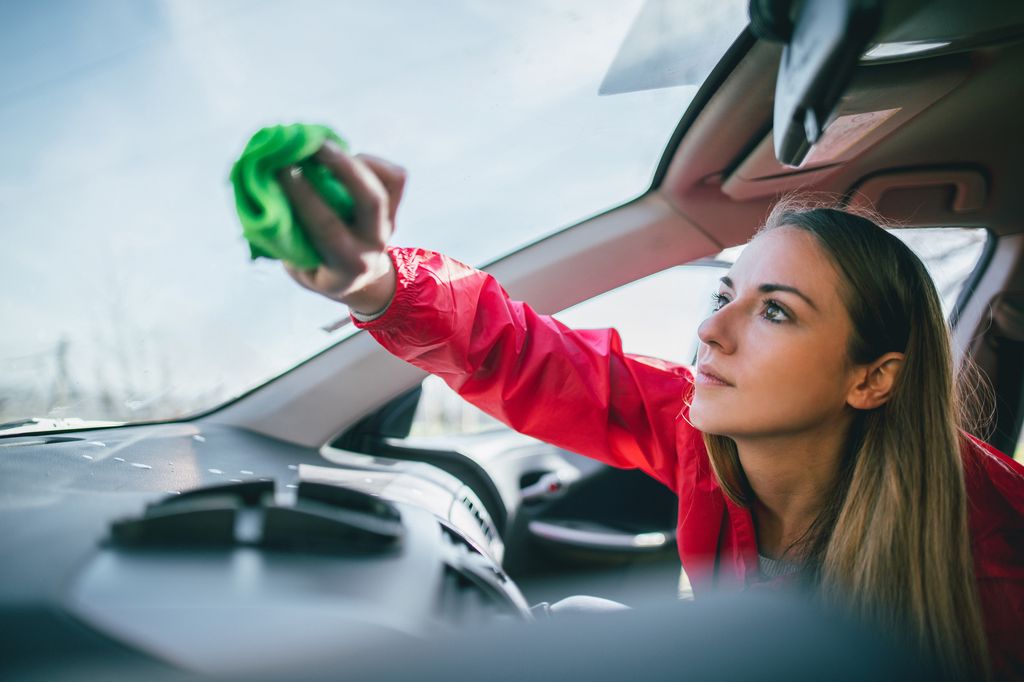 Young woman washing car and cleaning car windows