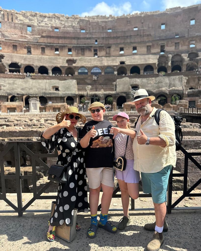 family of four posing with thumbs up