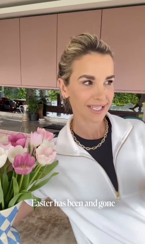 A woman in a white zip-up top stands in a modern kitchen, holding a bouquet of pink and white tulips. Text on the image reads, Easter has been and gone.