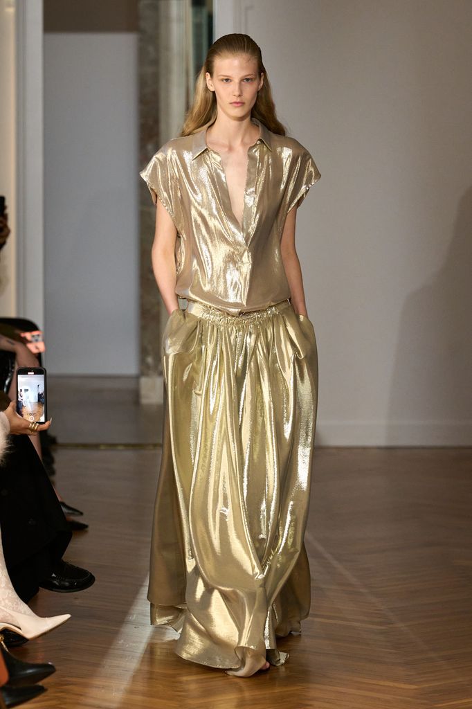 A model wears a liquid silk shirt top and maxi skirt in a light golden hue. 