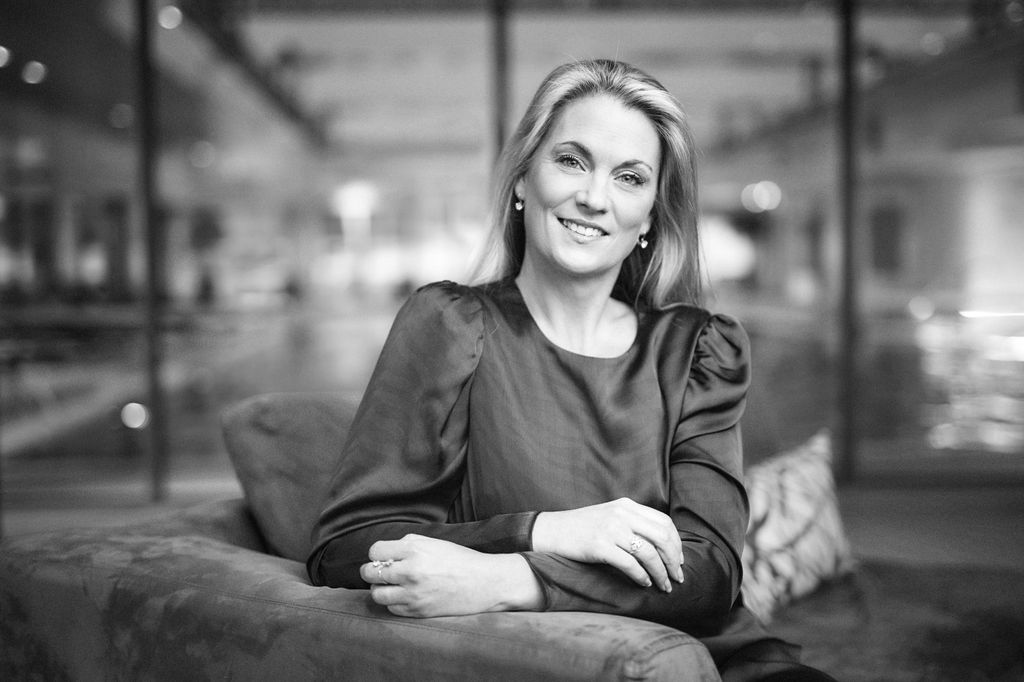 Blonde woman smiling in a smart dress in a black and white photo 