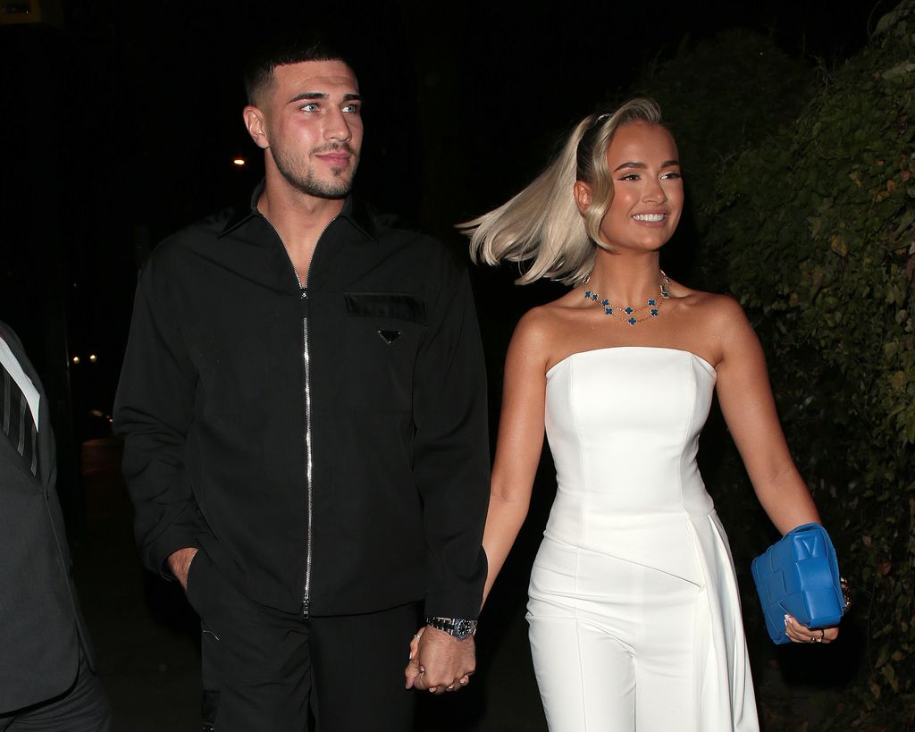 Tommy Fury in a black zip top and Molly-Mae in a white jumpsuit with her hair tied back in a ponytail