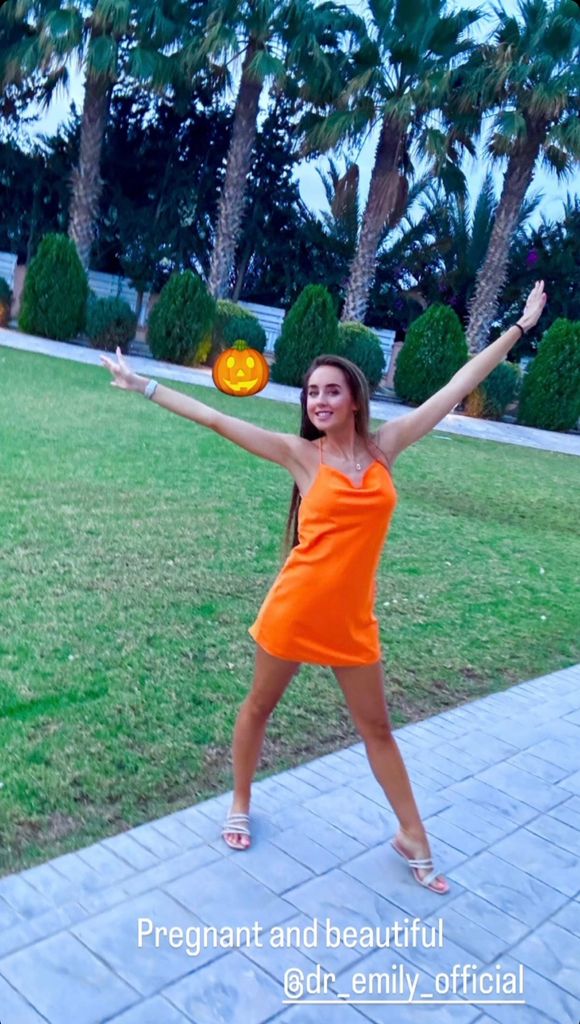 Emily Andre smiling in an orange dress in Cyprus 