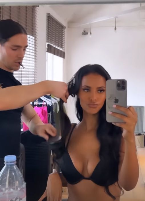 Maya Jama in a black bra getting hair brushed