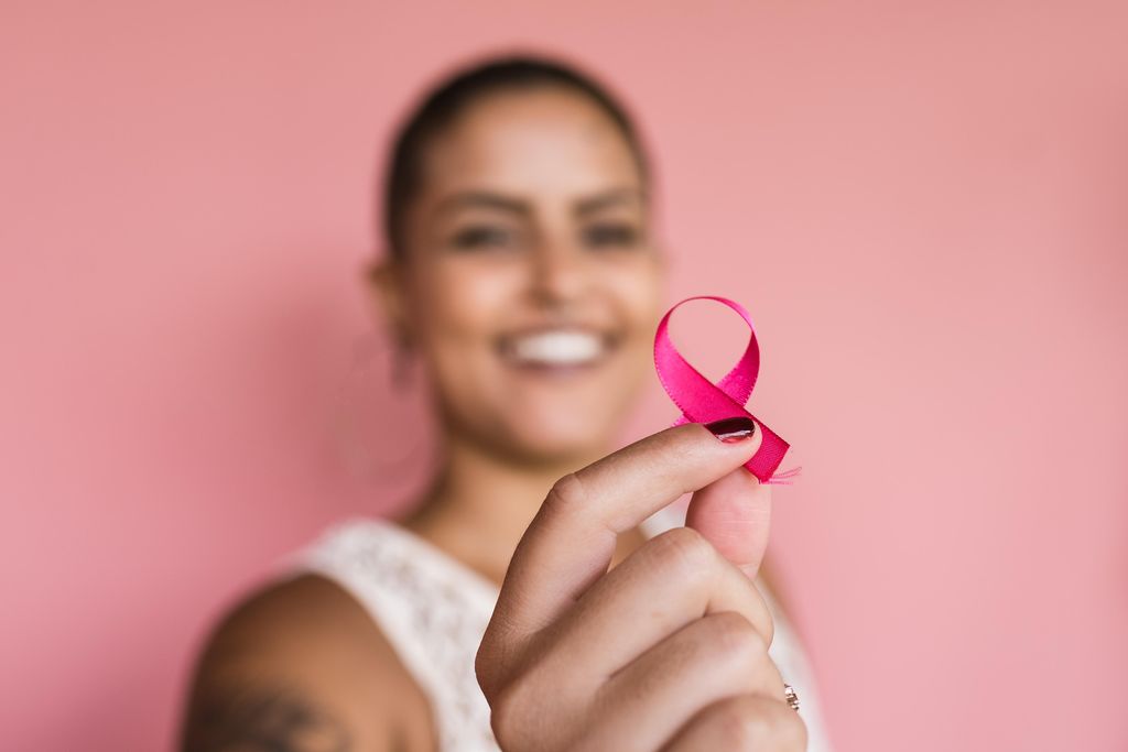 Woman holds pink ribbon for breast cancer awareness