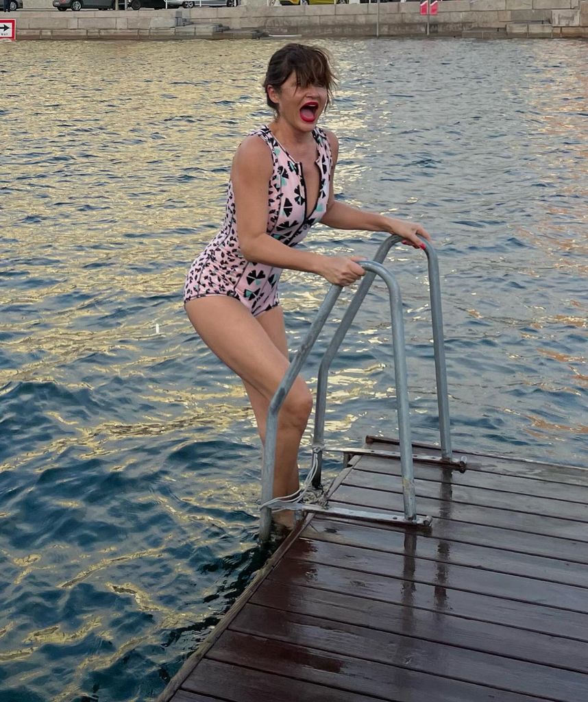 Helena Christensen with red lipstick and pink leopard print swimsuit braving cold water in Copenhagen