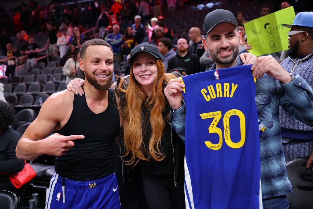 Stephen Curry #30 of the Golden State Warriors poses with actress Lindsay Lohan and her husband Bader Shammas