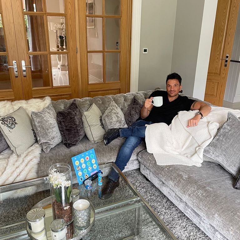 peter andre sentado no sofá de veludo em casa segurando uma caneca 