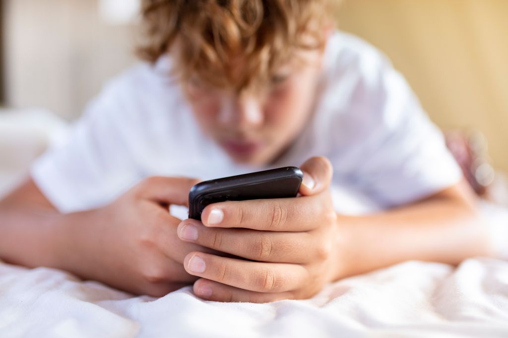 Boy look at phone on his bed