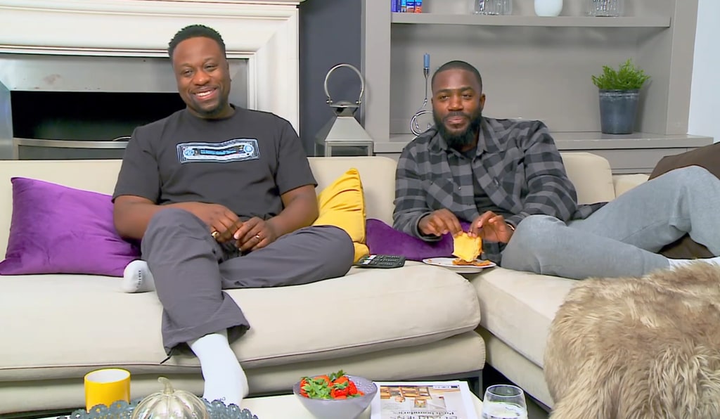 Babatunde Aleshe and Mo Gilligan sitting side by side on a cream sofa with coffee table in front of them