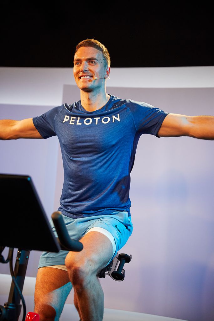 Man on a spin bike with his arms spread wide