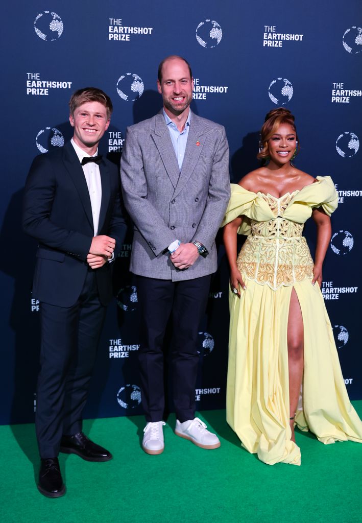 three people posing on green carpet
