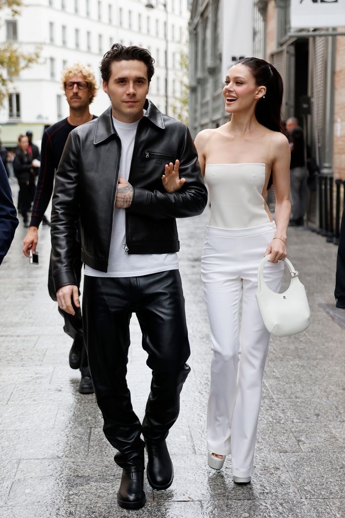 Brooklyn Beckham wears white t-shirt, black CourrÃ¨ges leather jacket, matching pants, black boots, and Nicola Peltz wears white jumpsuit with sheer details, white CourrÃ¨ges bag, outside CourrÃ¨ges,  during Womenswear Spring/Summer 2025 as part of  Paris Fashion Week on September 25, 2024 in Paris, France. (Photo by Claudio Lavenia/Getty Images)