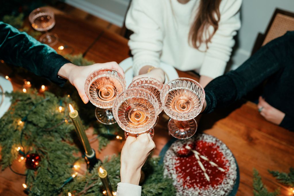 top-down shot of friends toasting over a Christmas dinner table
