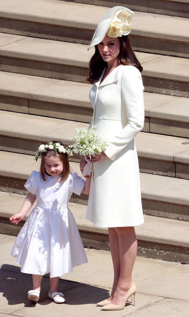 Princess Kate in a white coat dress holding hands with Princess Charlotte 