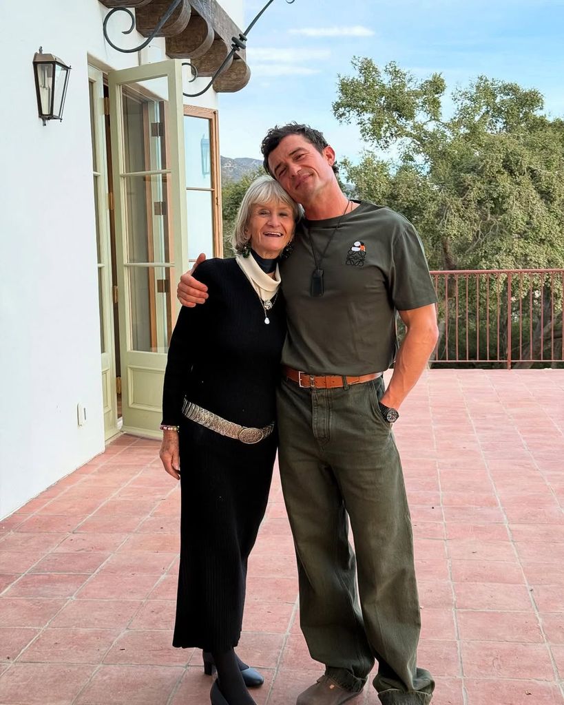 Orlando Bloom putting his arm around his mom standing on the terrace of his Californian home