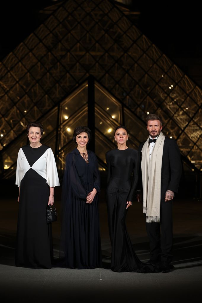 four people posing in front of louvre