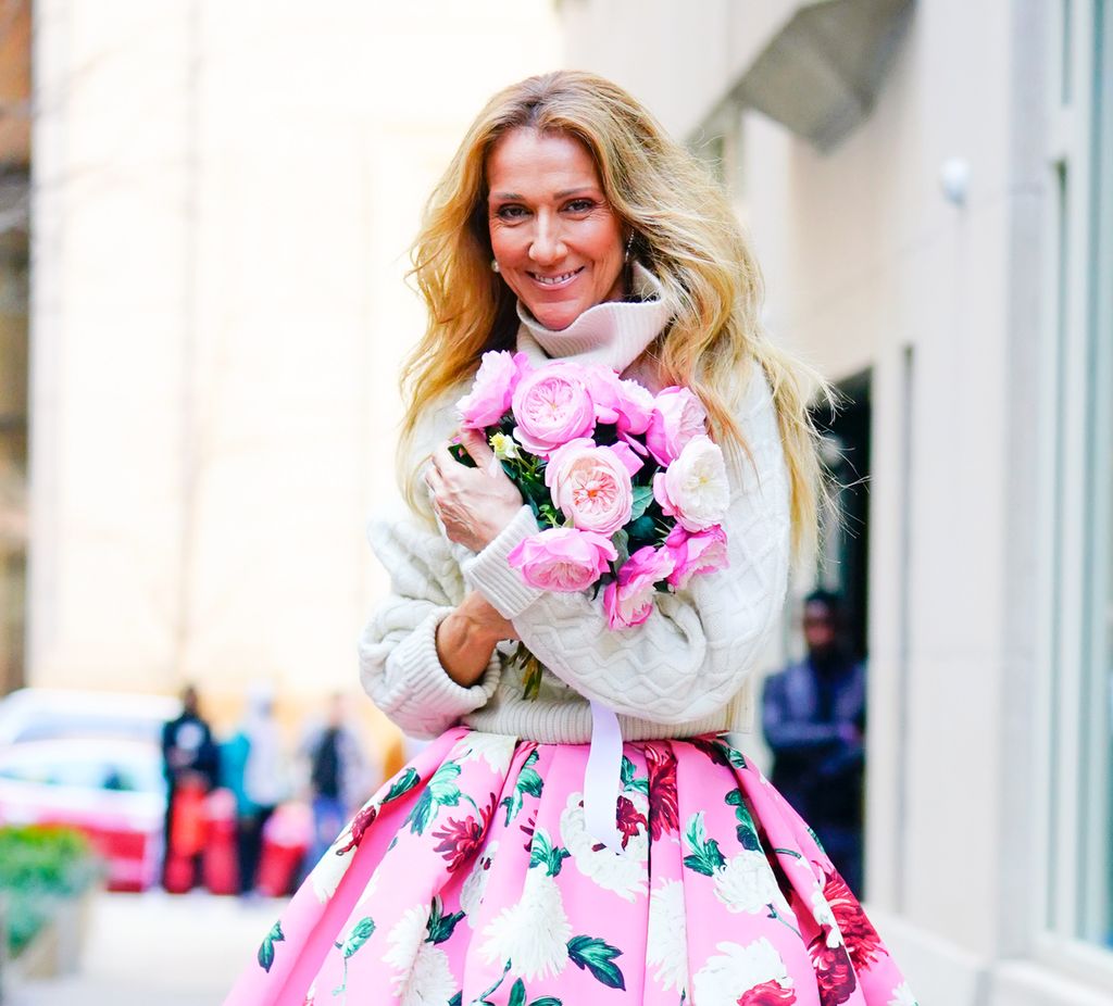 Celine Dion smiling and holding pink flowers in 2020 in NYC 