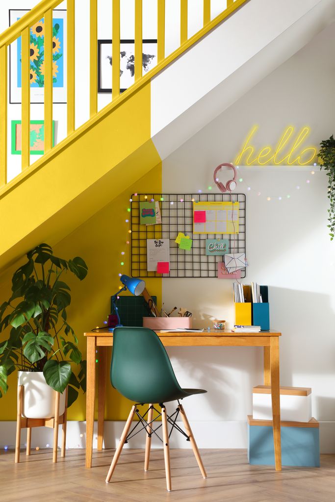 A colourful desk space under stairs