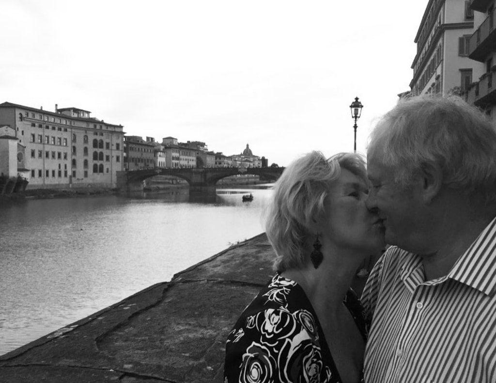 Photo shared by Catherine Zeta-Jones on Instagram October 22, 2023 in honor of her parents David and Patricia's 57th wedding anniversary, where the two are sharing a kiss by a river.