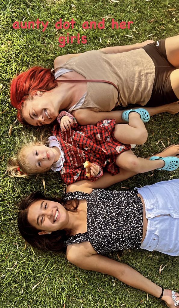 Dianne laying on grass with her lookalike nieces