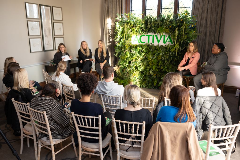 People sitting on chairs watching a panel discussion with an Activia sign