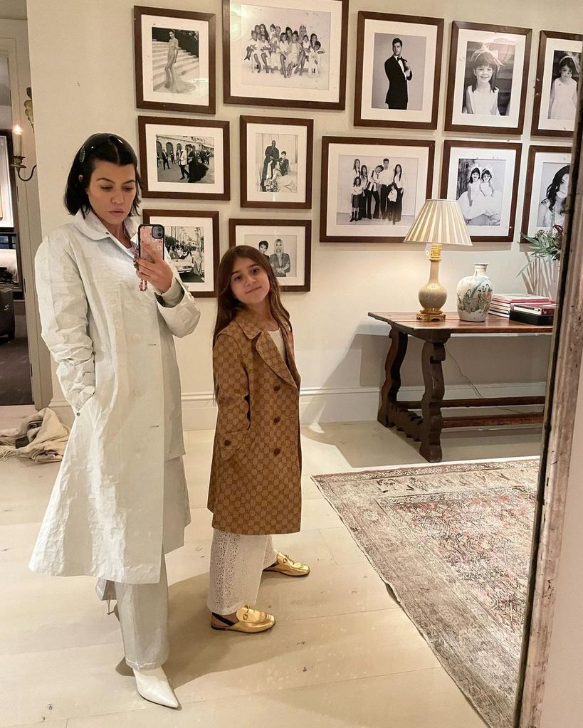 Kourtney Kardashian e a filha Penelope em frente a uma parede da galeria