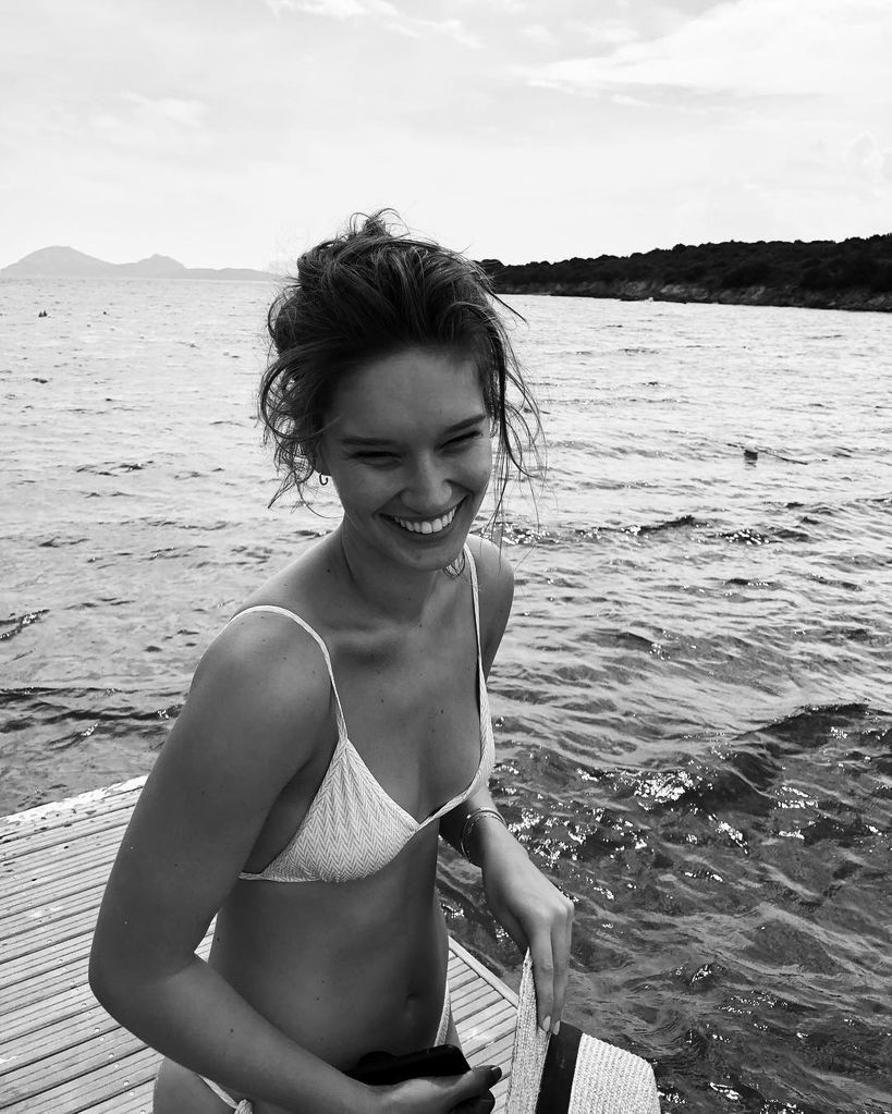 black and white photo of a woman in a bikini by the sea