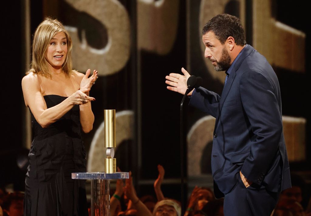 Jennifer Aniston presents Adam Sandler with the People's Icon Award onstage during the 2024 People's Choice Awards held at Barker Hangar on February 18, 2024 in Santa Monica, California.