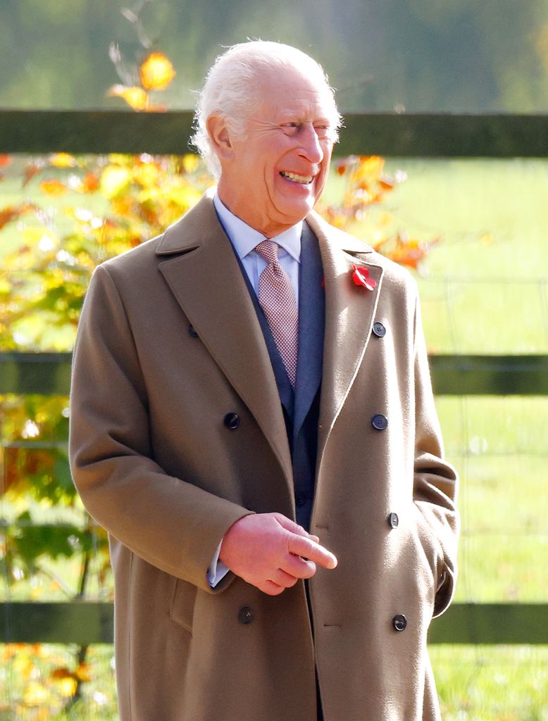 King Charles smiling in a brown coat