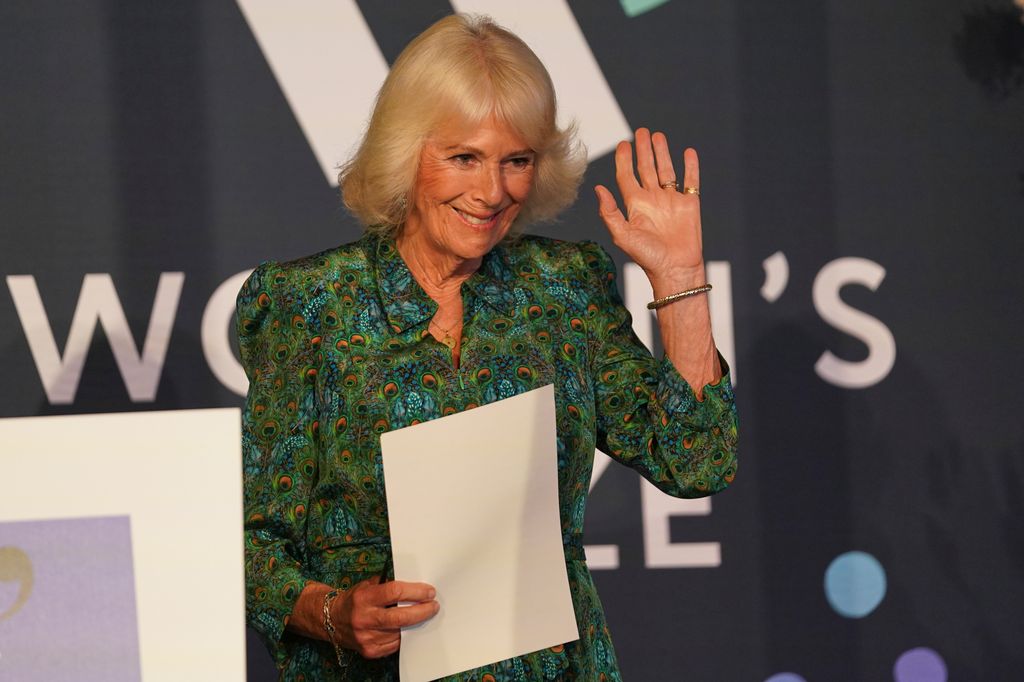 Queen Camilla waving to a crowd following a speech