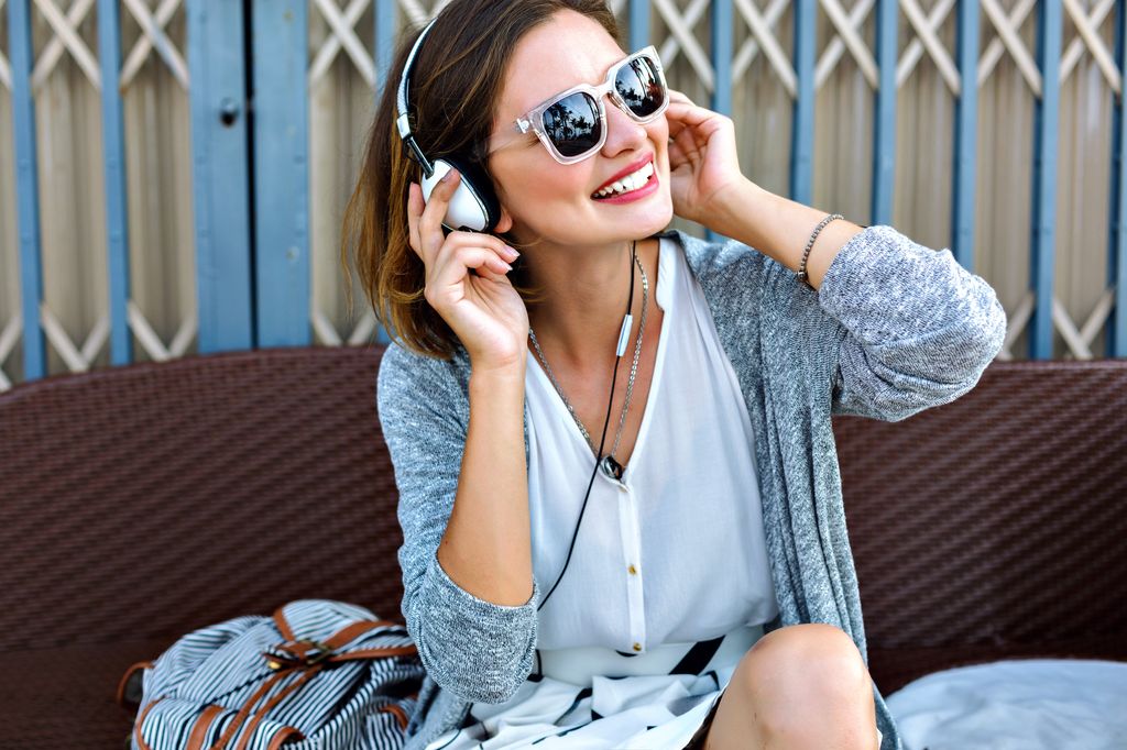 young woman listening to music on headphones and smiling
