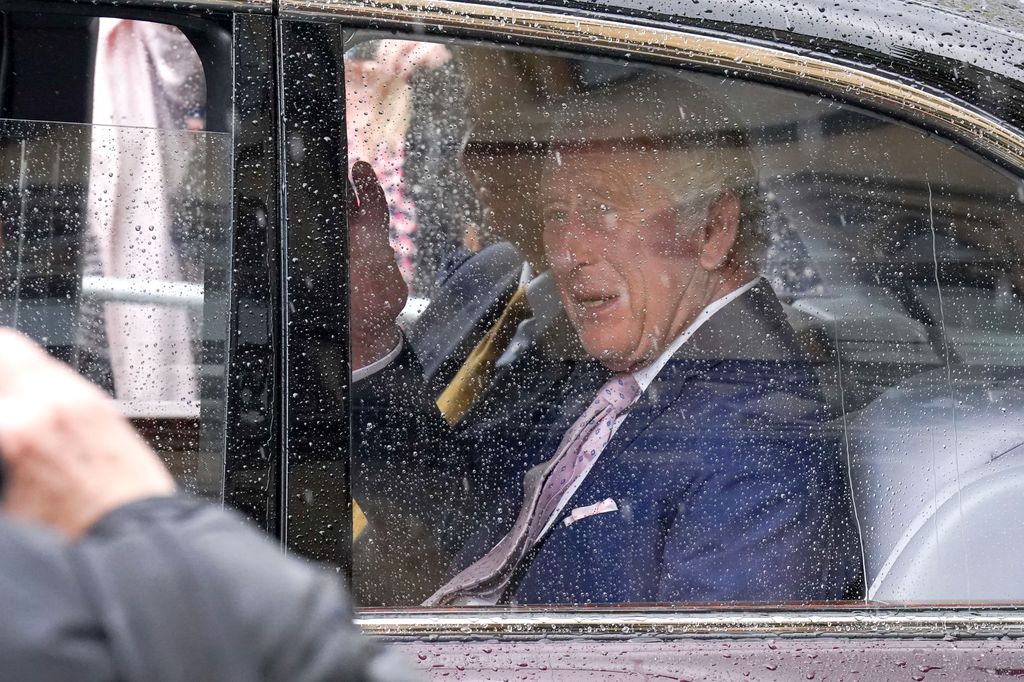 King Charles waved to fans gathered outside in the rain