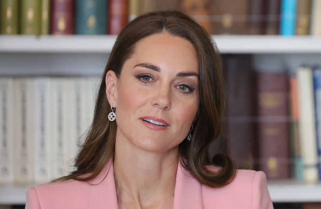 Kate Middleton listens in front of bookcase 