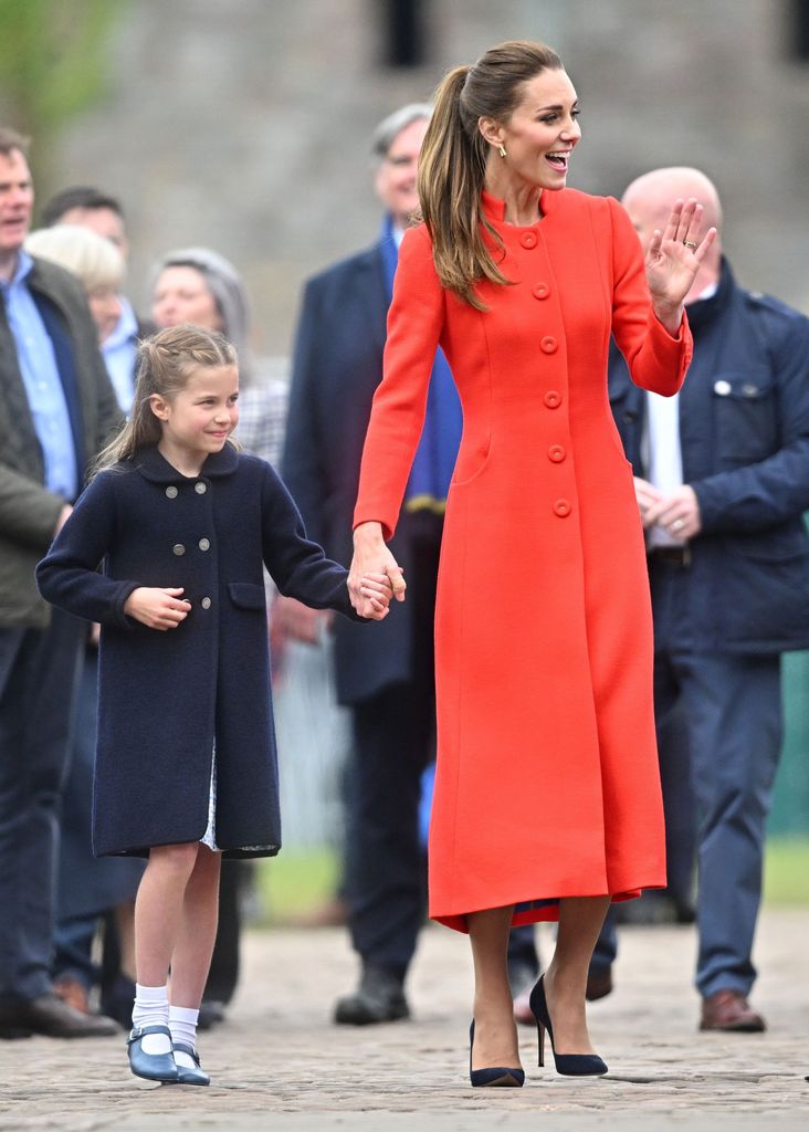 Kate Middleton wearing red coat and holding Princess Charlotte's hand in Cardiff
