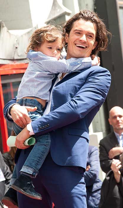 Orlando Bloom smiling as he holds a young Flynn