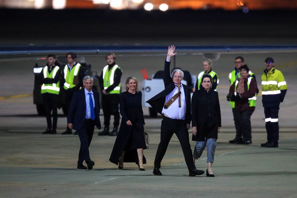 Julian Assange gestures as he arrives at Canberra Airport 