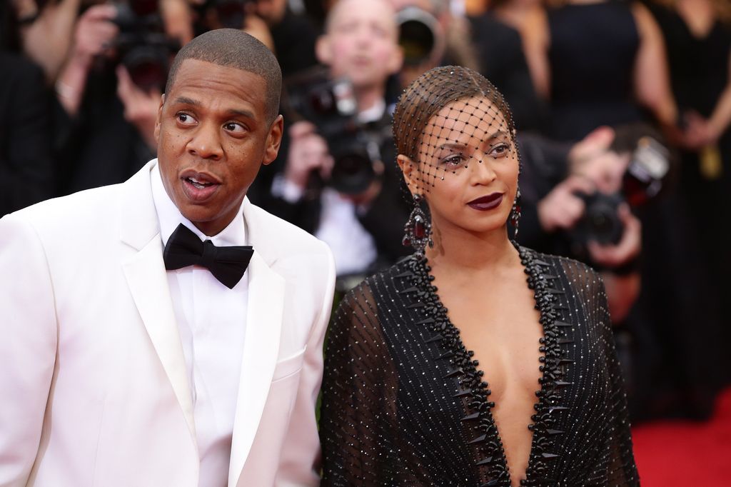 Beyonce in a black dress and veil standing next to Jay-z in a white suit