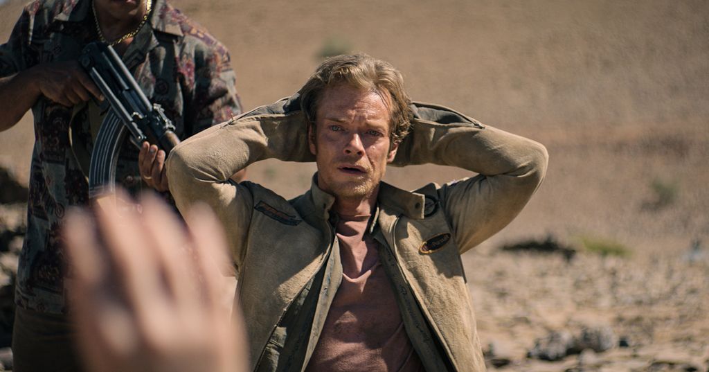 Man sits with hands behind his head
