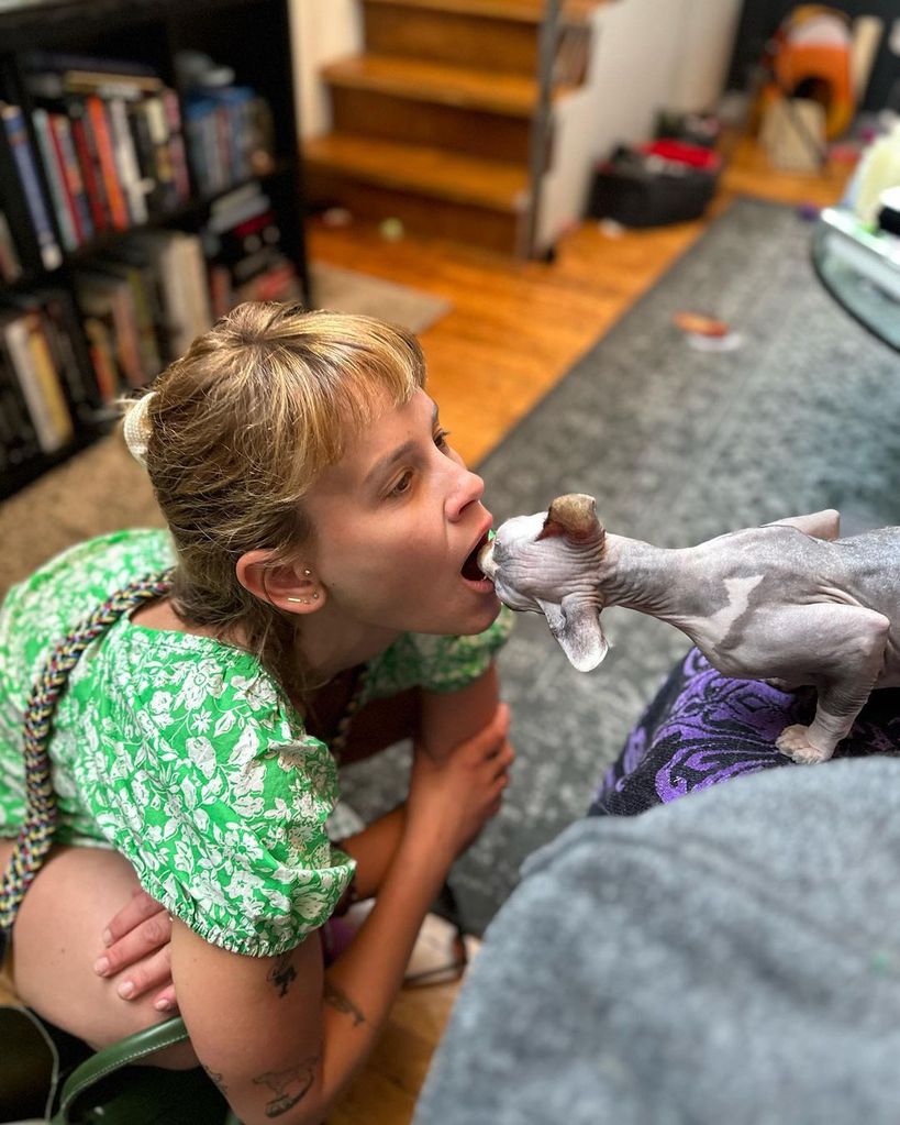Sosie Bacon opens her mouth for her cat